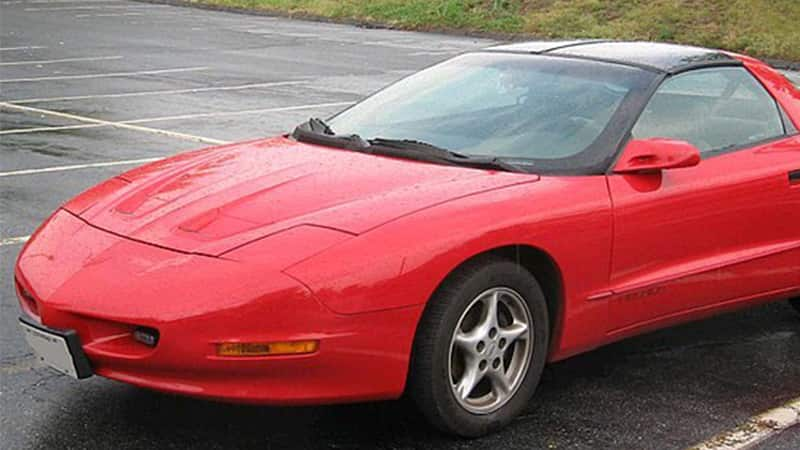 A bright red Firebird in a parking lot.