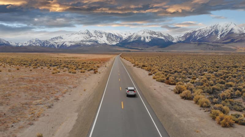 car on road driving toward mountains