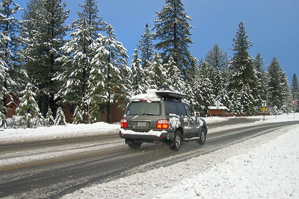 An SUV drives down a snow-lined street