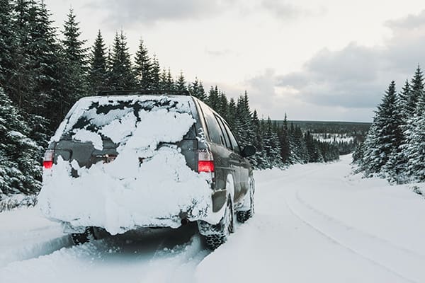 A gray SUV travels down a snow-covered road.